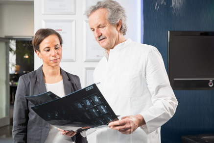 Dr. Dr. Engelke und Mitarbeiterin besprechen Röntgenaufnahmen